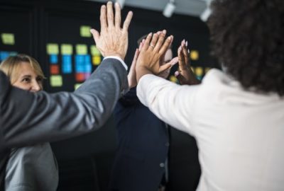 Group of colleagues high fiving one another at a support session for mental health